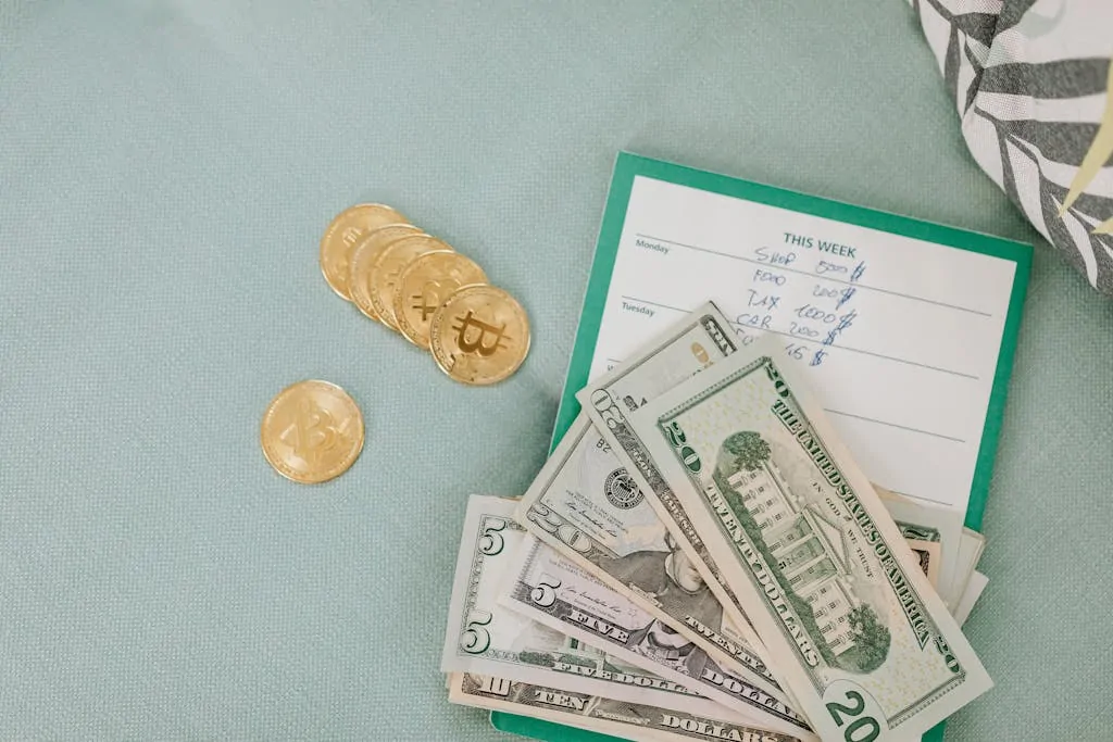 11 Easy Money Hacks You’ll Wish You Knew 1 Close-up of U.S. dollars and Bitcoin coins placed on a weekly budget planner, symbolizing modern finance.