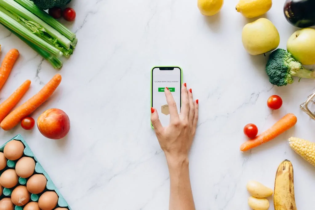 Eat Healthy on a Budget (Simple Tips) 1 Flat lay of fresh vegetables and fruit with a smartphone showing grocery delivery confirmation.